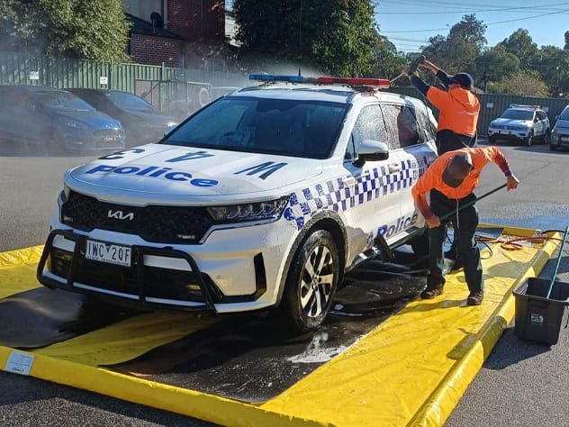 Vehicle using a portable wash bay with drive-on access ramps