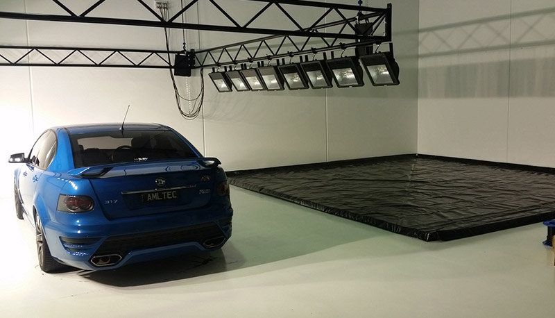 Portable wash bay with black containment mat installed indoors for controlled vehicle washdown